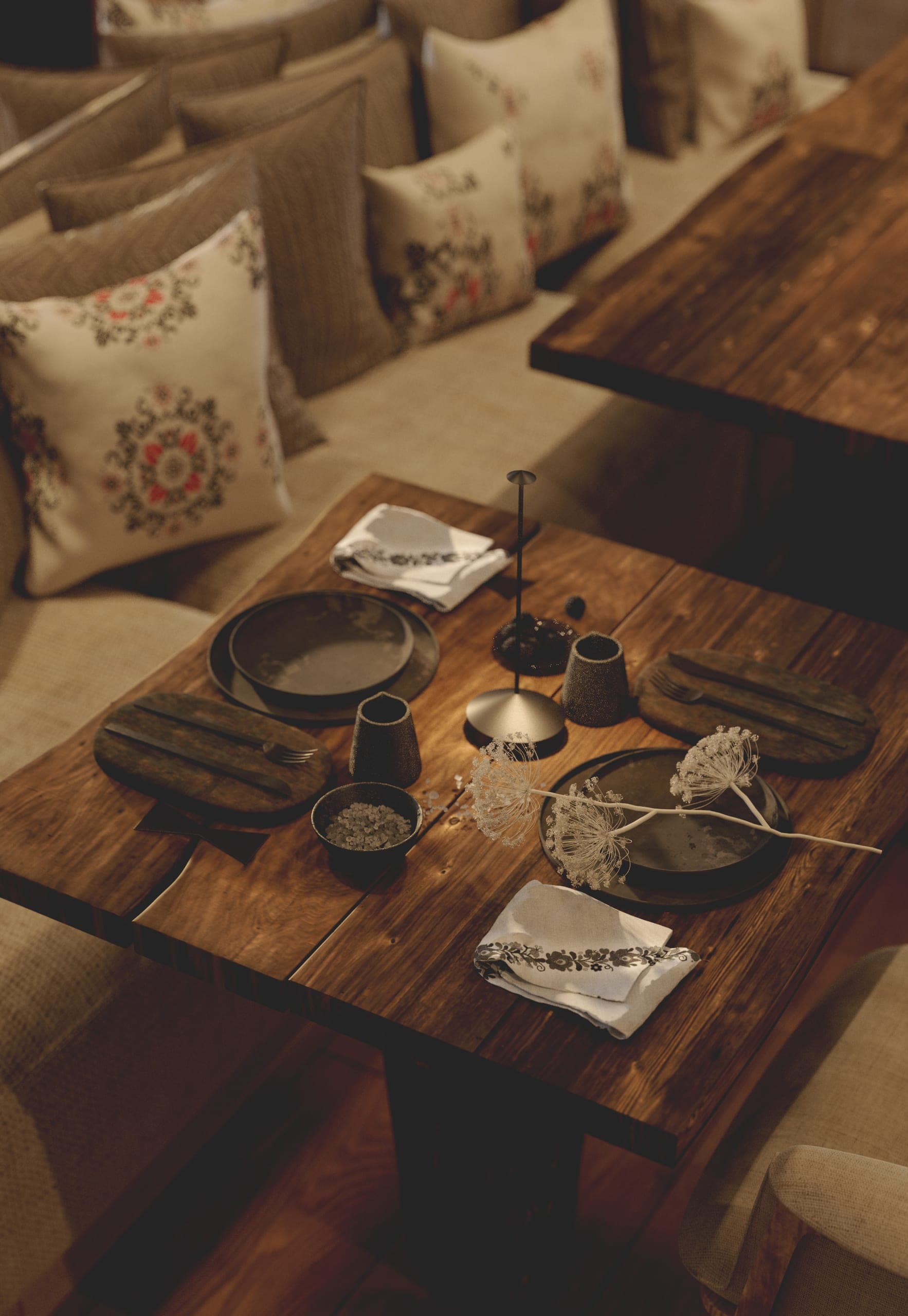 Stup Restaurant: timber table set with ceramics and embroidered cushions, seen from above